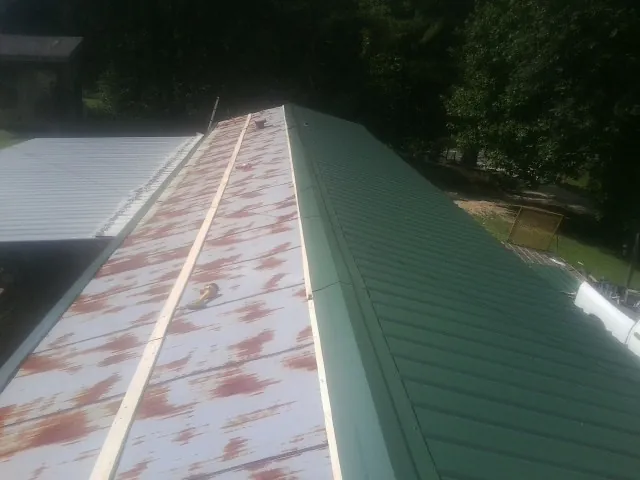 Old rusted panels beside newly installed green metal roofing — Wind Damage Roof Repair by Roofing Brothers in Fairmont