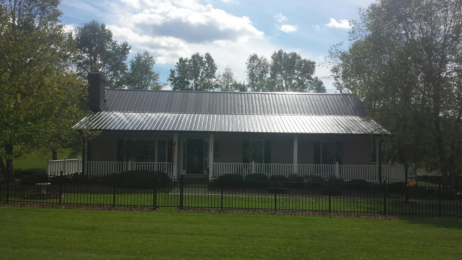 Gray metal roof on a brick ranch with a full width front porch — Gutter Guard Installation work by our crew in Fairmont