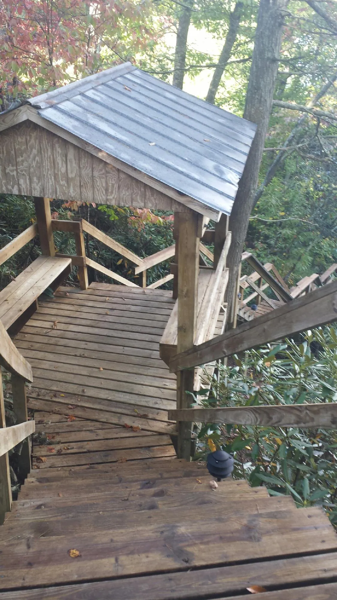 Metal roofed shelter over wooden steps on a wooded walkway — Skylight Repair & Installation work by our crew in Fairmont