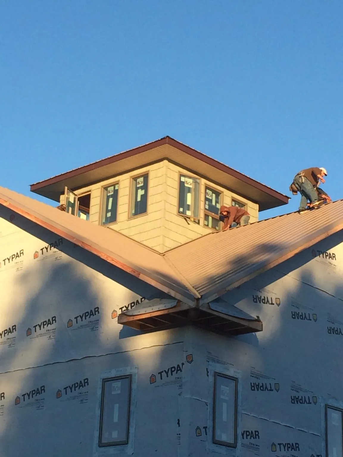Roofers working around a rooftop cupola on a new metal roof at sunset — Roof Waterproofing in Fairmont by Roofing Brothers